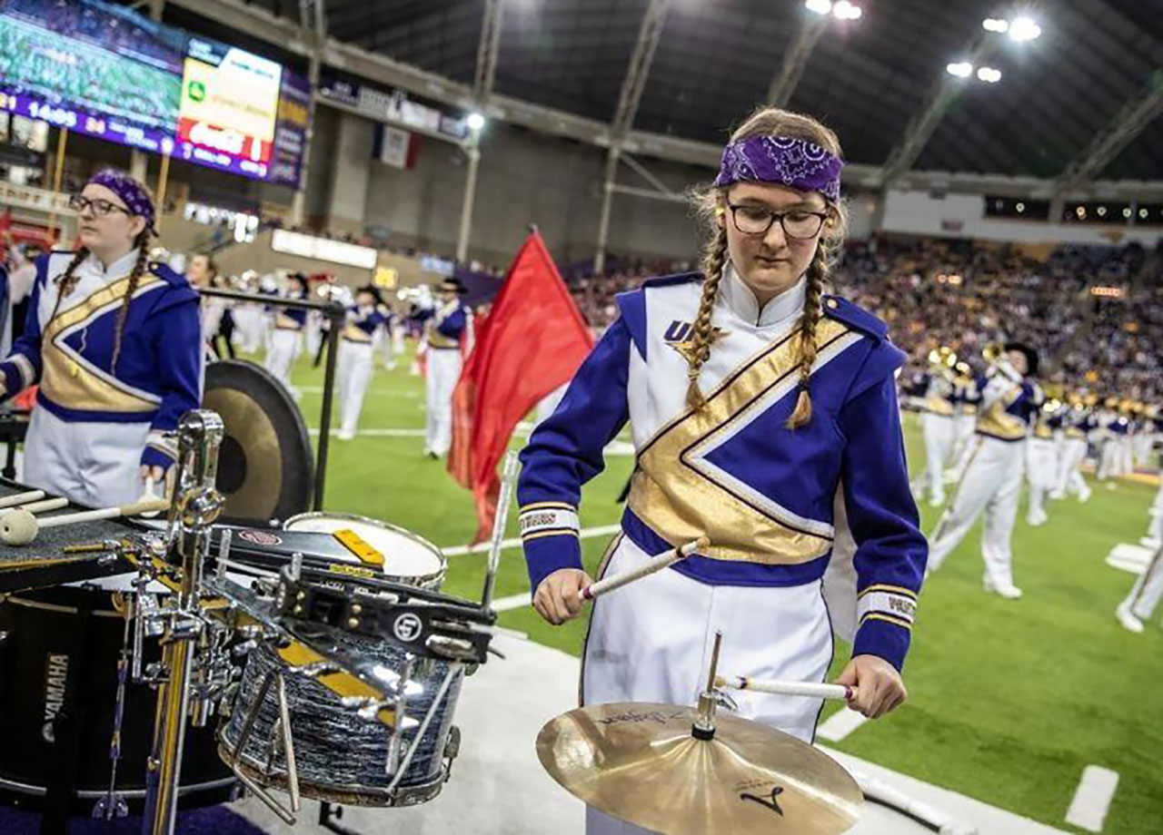 Student playing a snare at a football game.
