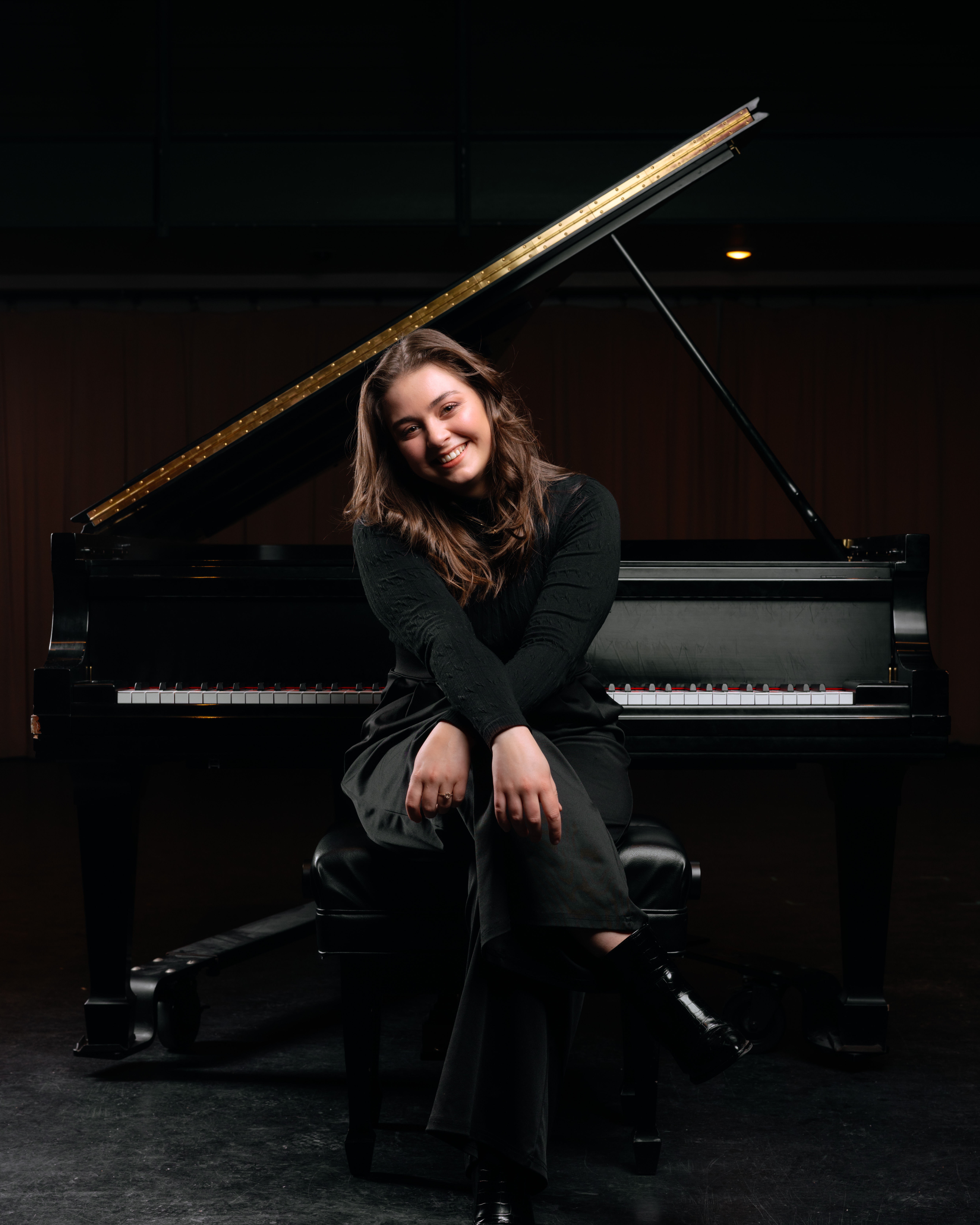 Madelyn Potter sitting in front of a grand piano.