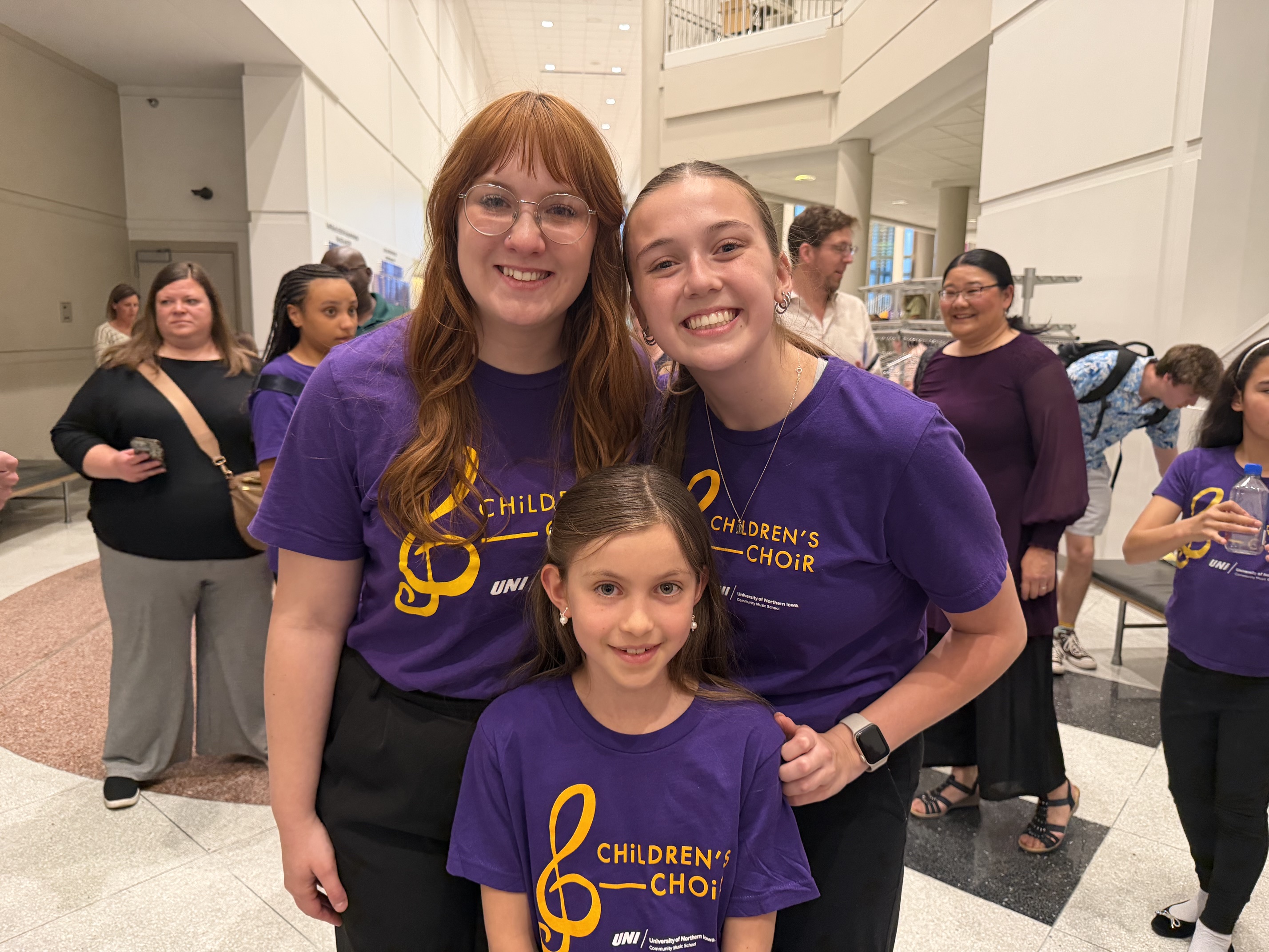Assistands Akela and Abby standing with choir member after a concert