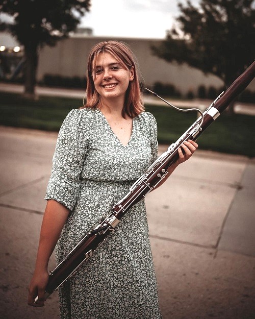 Kate VanGorp standing outside holding bassoon