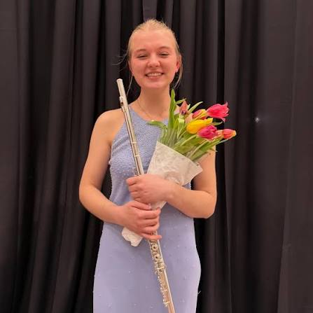 Bethany standing holding a flute and bouquet of tulips.