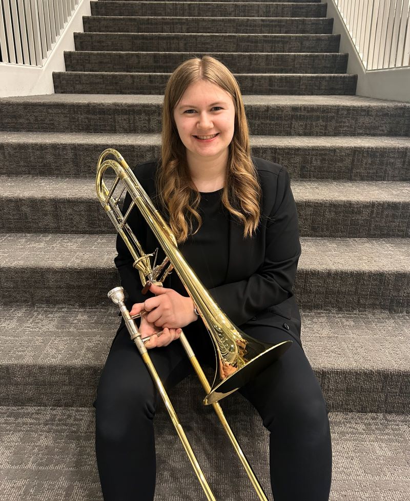 Morgan sitting on steps holding trombone