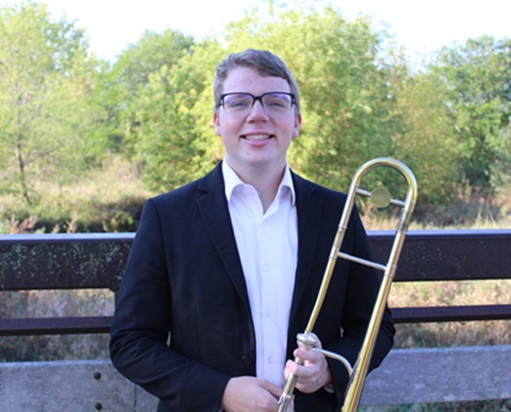 Levi Temple standing outside, holding trombone