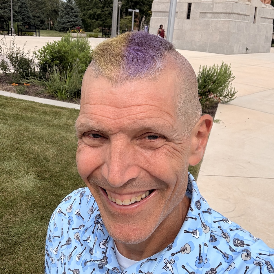Headshot of Kevin Droe with purple and gold Mohawk
