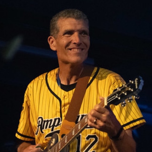 Photo of Kevin Droe in yellow baseball jersey playing guitar
