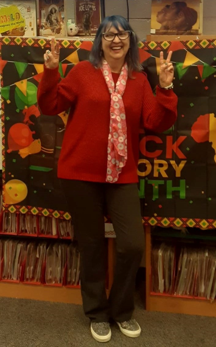 Crystal Waltz standing showing peace signs on both hands.