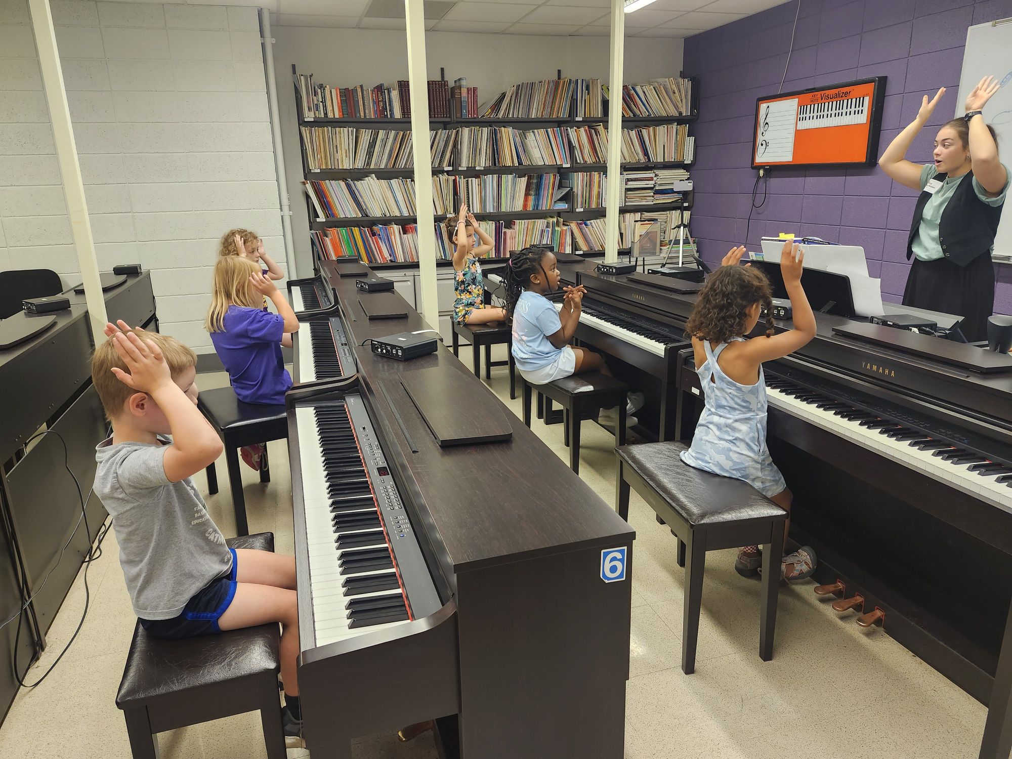 Madelyn Potter leading a group piano class with young students.