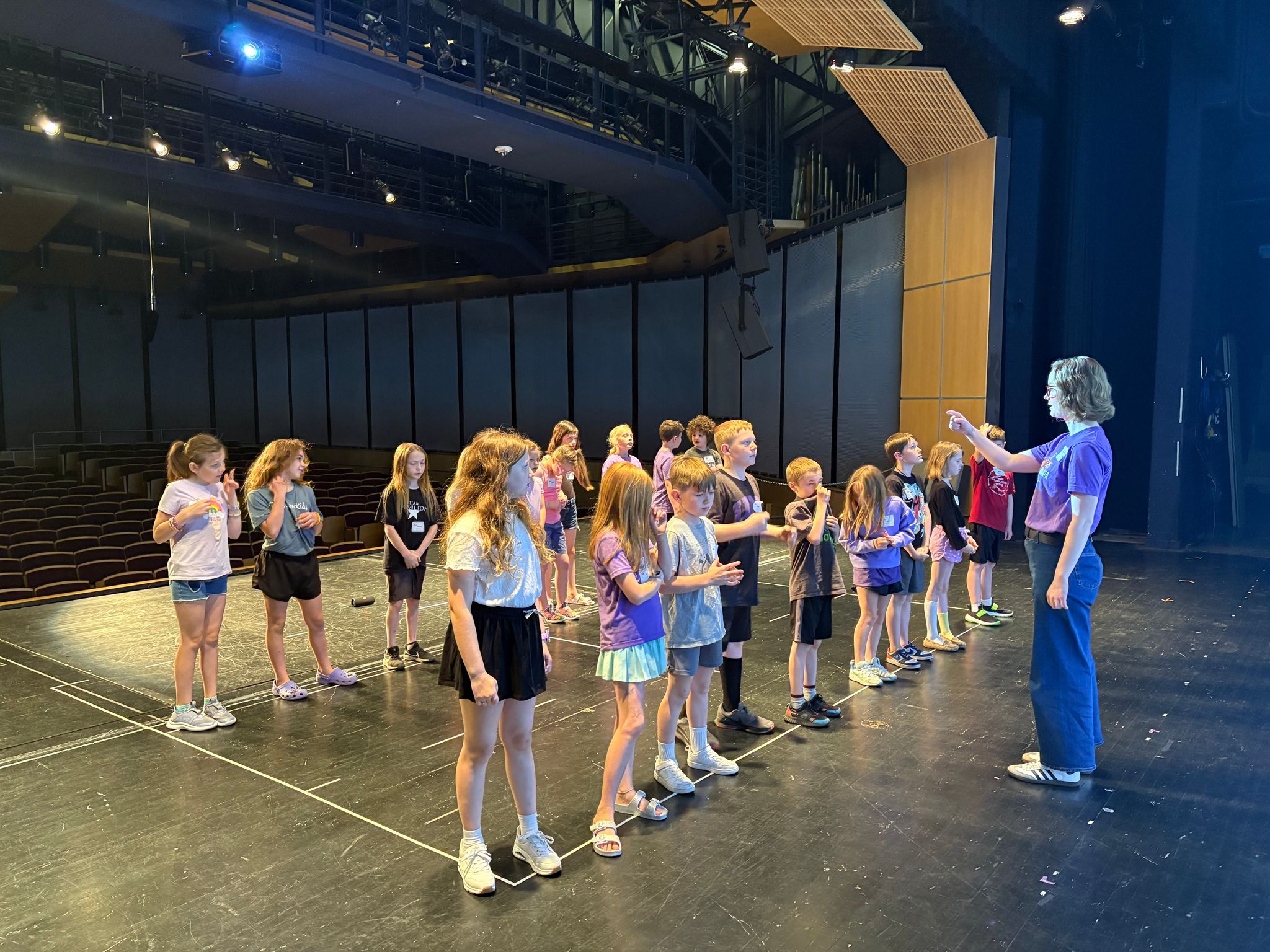students standing in two lines on stage practicing moves for musical performance
