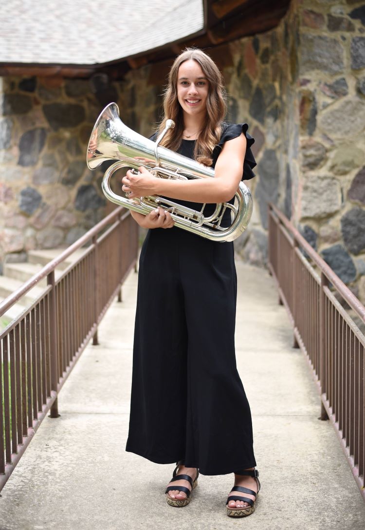Morgan Westphal wearing a black dress, standing and holding a euphonium in front of her