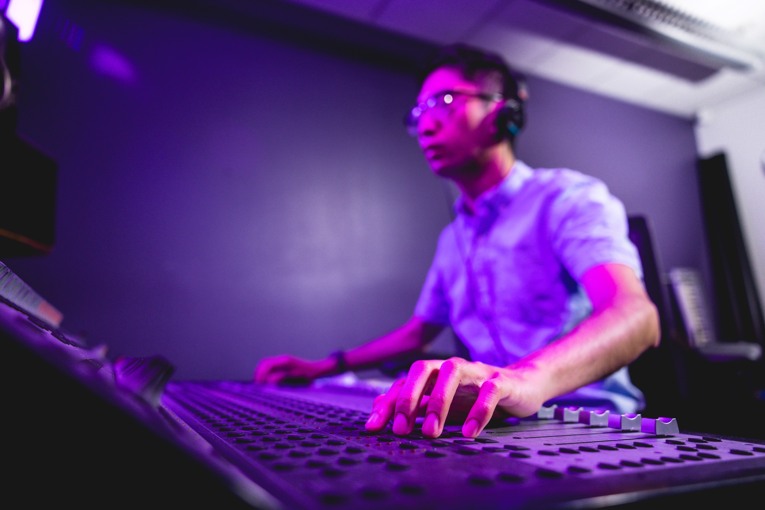 student with headphones on with hand on a sound recording board