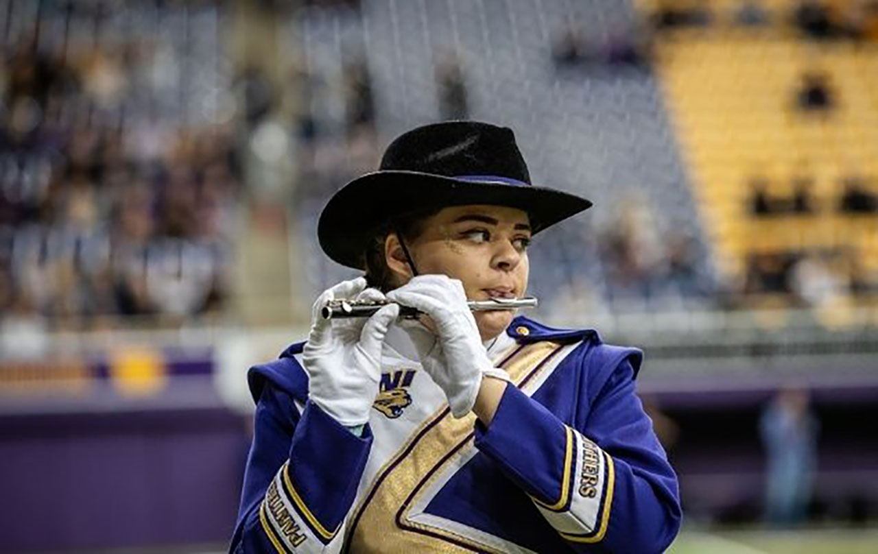 Student playing a flute at a football game.