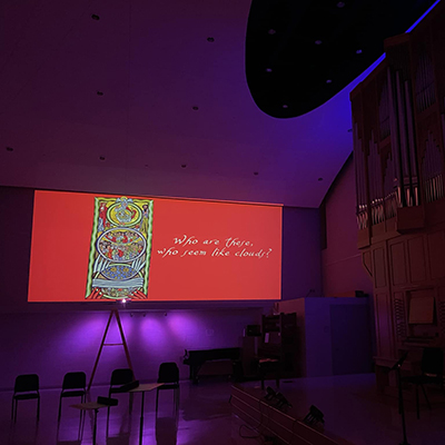 Jebe Hall with mood lighting, a slide with lyrics from Ordo Virtutum is projected on the wall