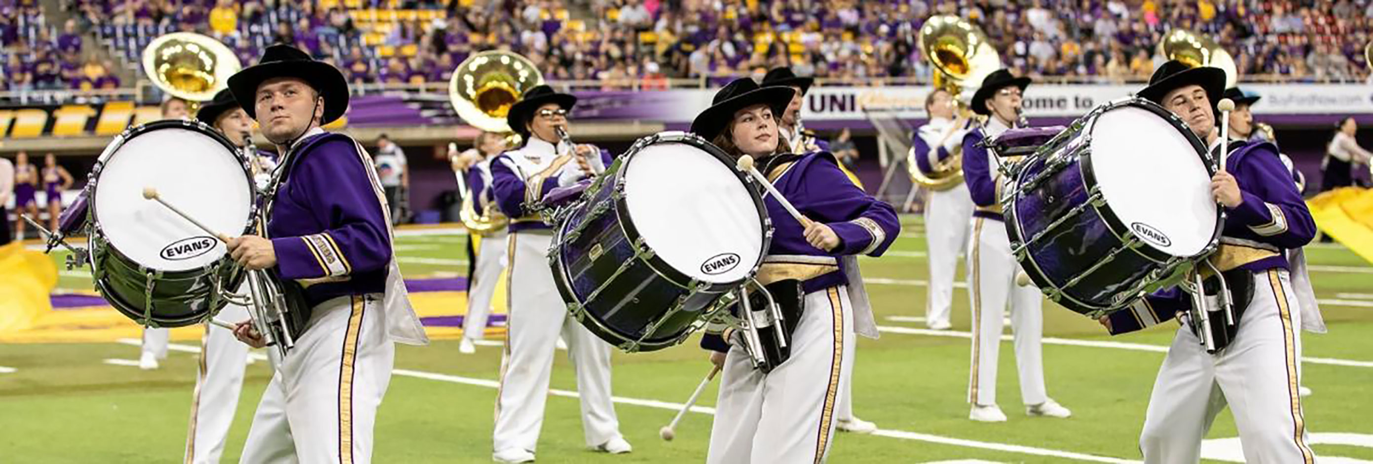 Students playing drums on a football field.