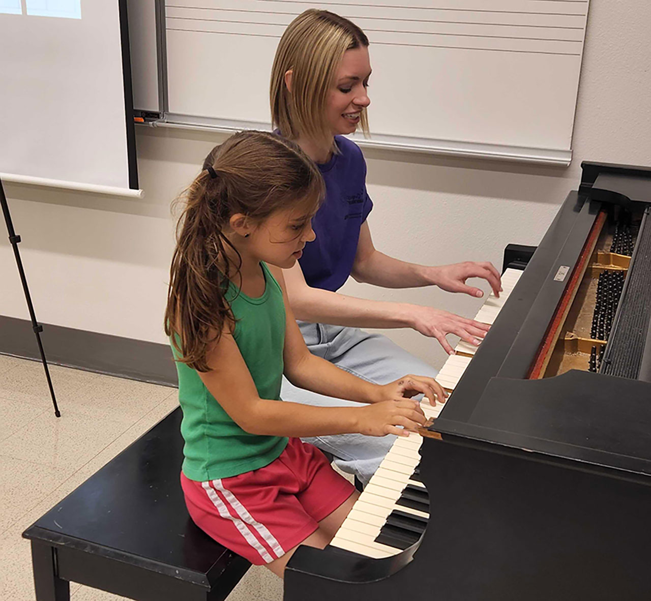 Student with an instructor at a piano.