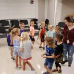 Kids walking in a circle with teacher singing