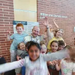 Dr. Swilley posing with group of kids waving and showing the peace sign