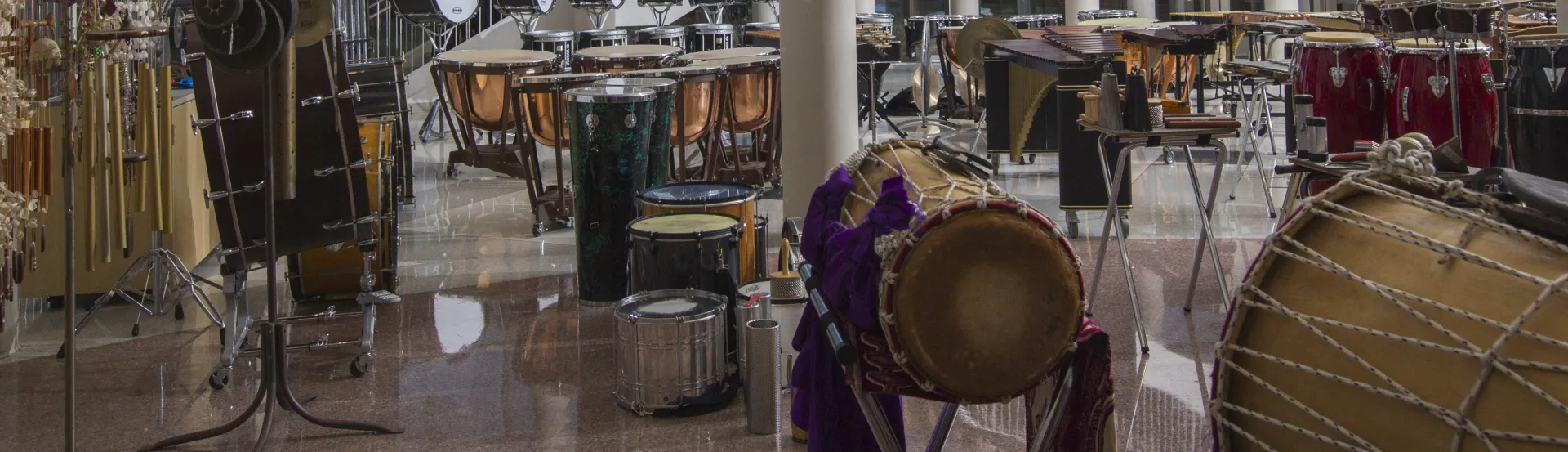 A large number of percussion instruments and students lined up on a staircase behind them